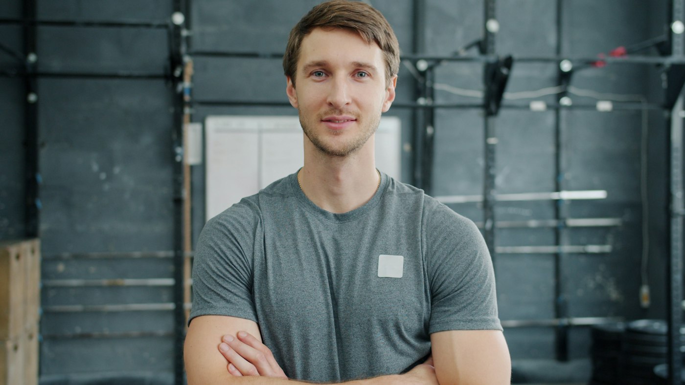 Coach sportif, bras croisés, dans sa salle d'entraînement