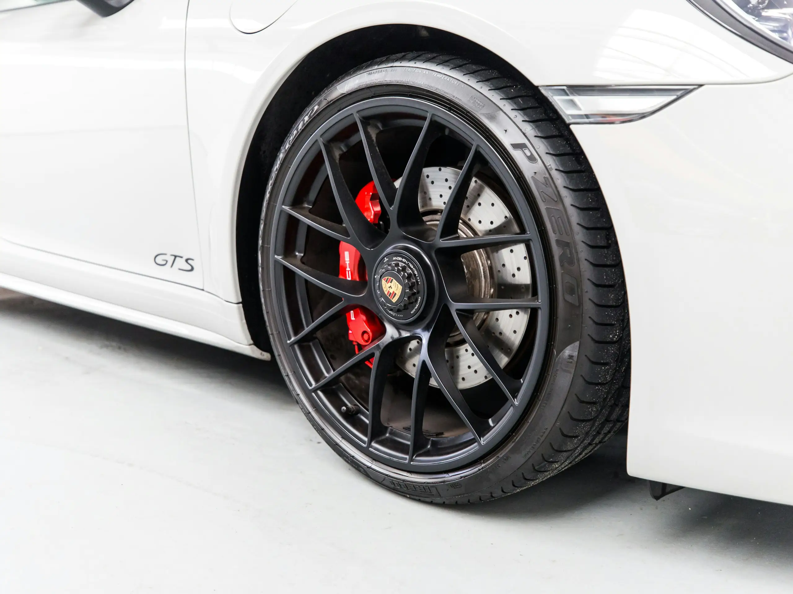 Roue avant d’un coupé blanc : jante noire et étrier rouge