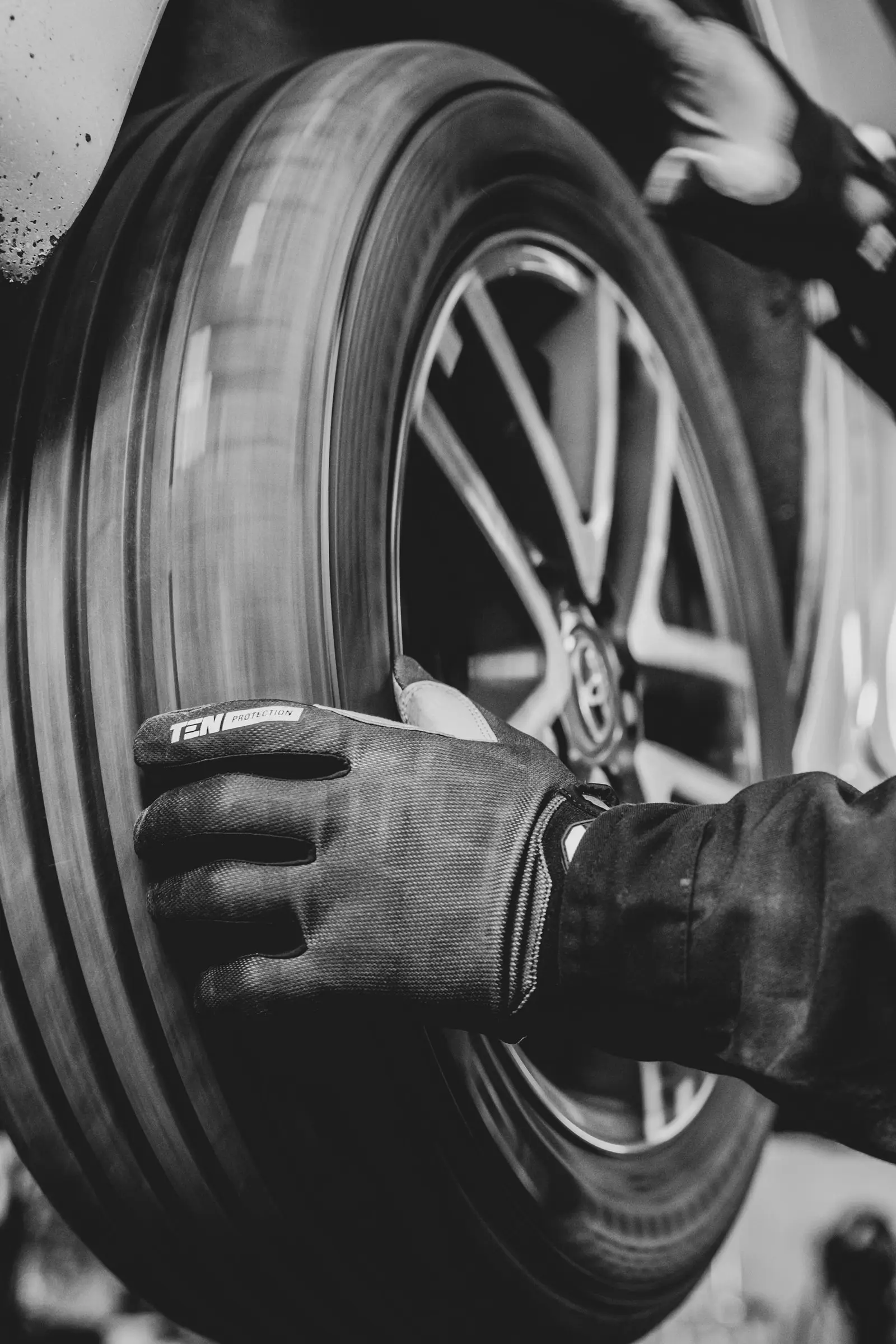 Main gantée tenant une roue, en noir et blanc